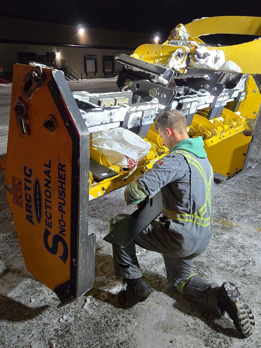 Shawn Neels repairing an Arctic snow pusher late at night before a storm